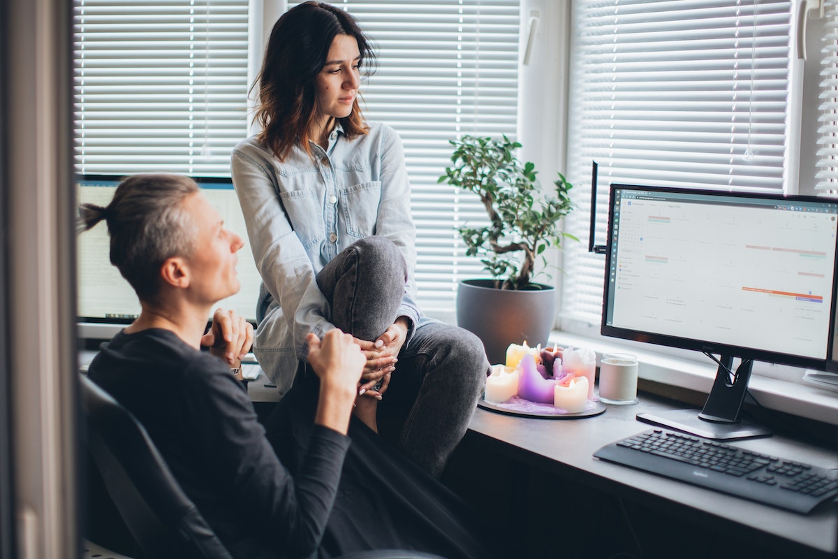 A man and a women sitting a desk looking at a computer monitor showing a Google calendar.