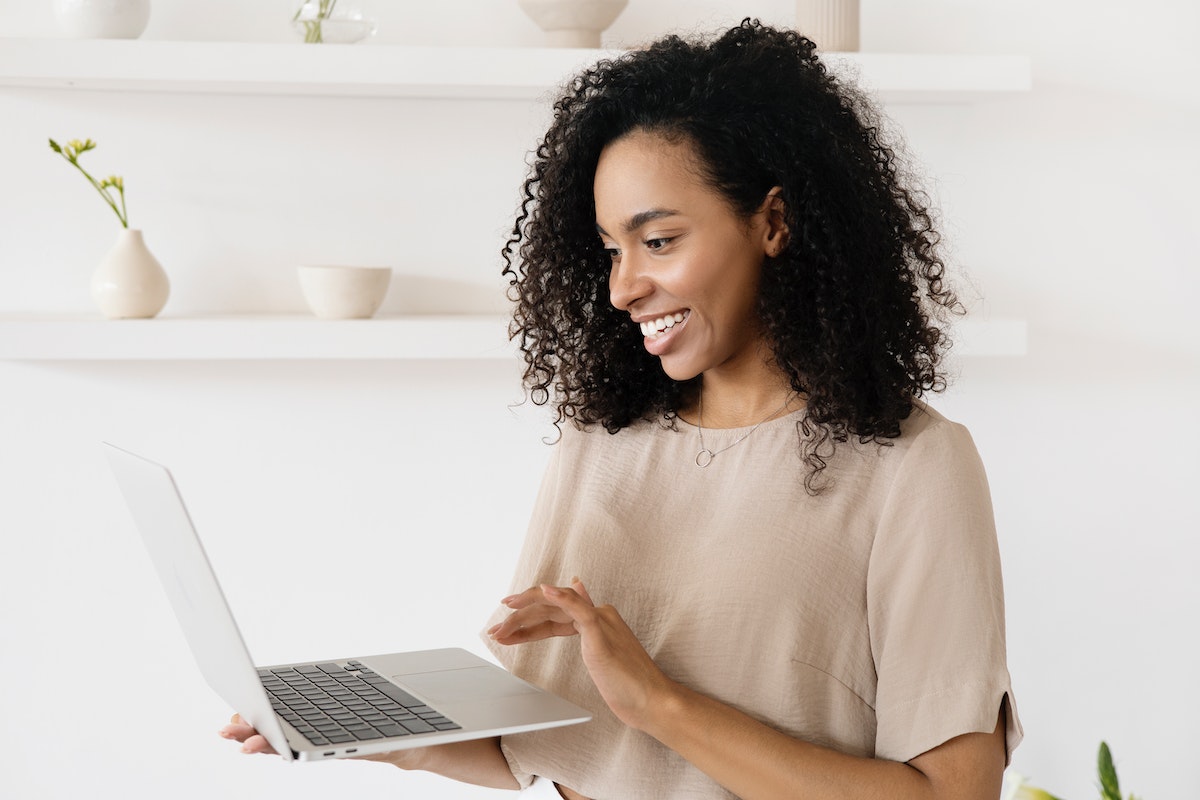 A woman smiling while looking at her online booking system on a laptop